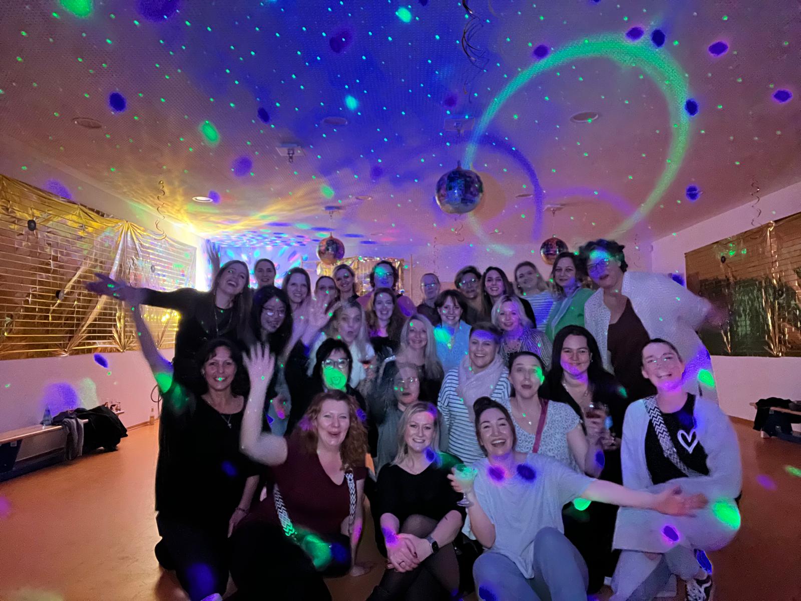 Gruppenbild mit cirka 30 Frauen in einem bunt zur Diskothek dekorierten Raum