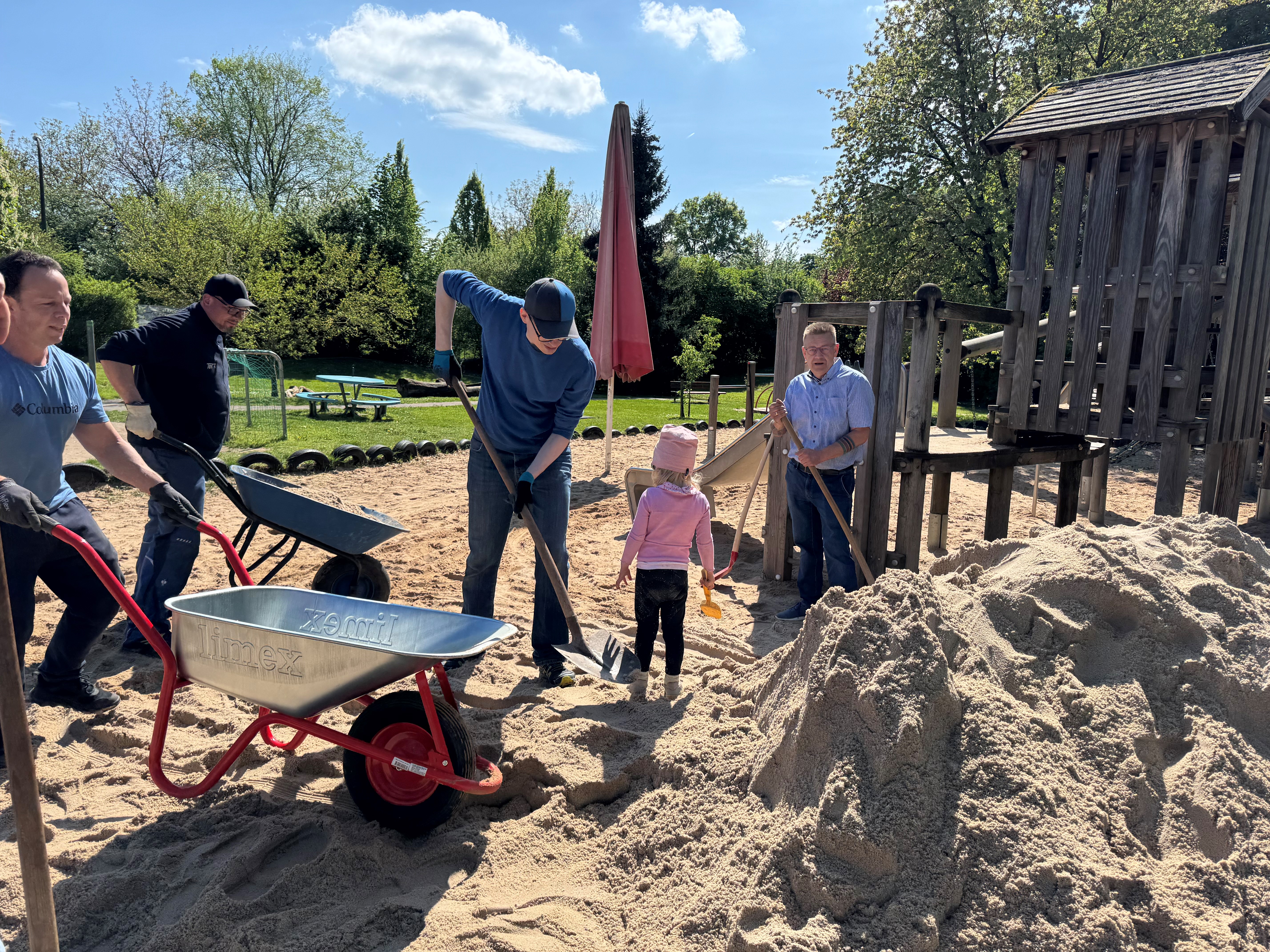Eltern, Kinder und Bürgermeister beim Sandschaufeln