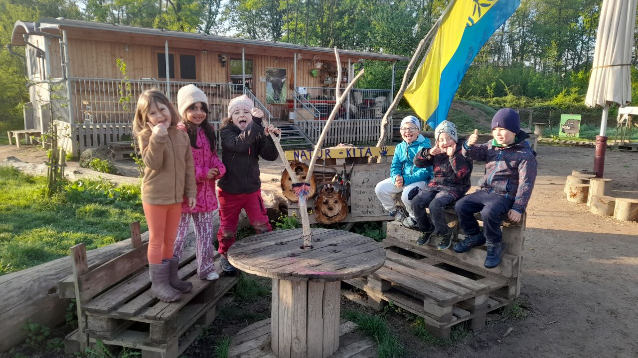 Fröhliche Kinder vor dem Bauwagen der NaturKiTa