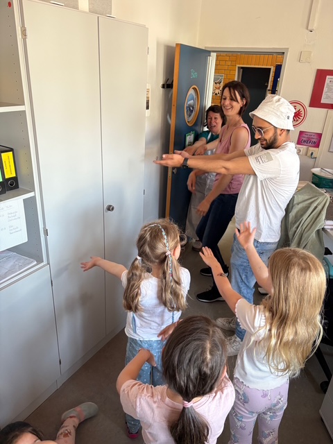 Erzieher und Erzieherinnen tanzen mit Kindern im Büro