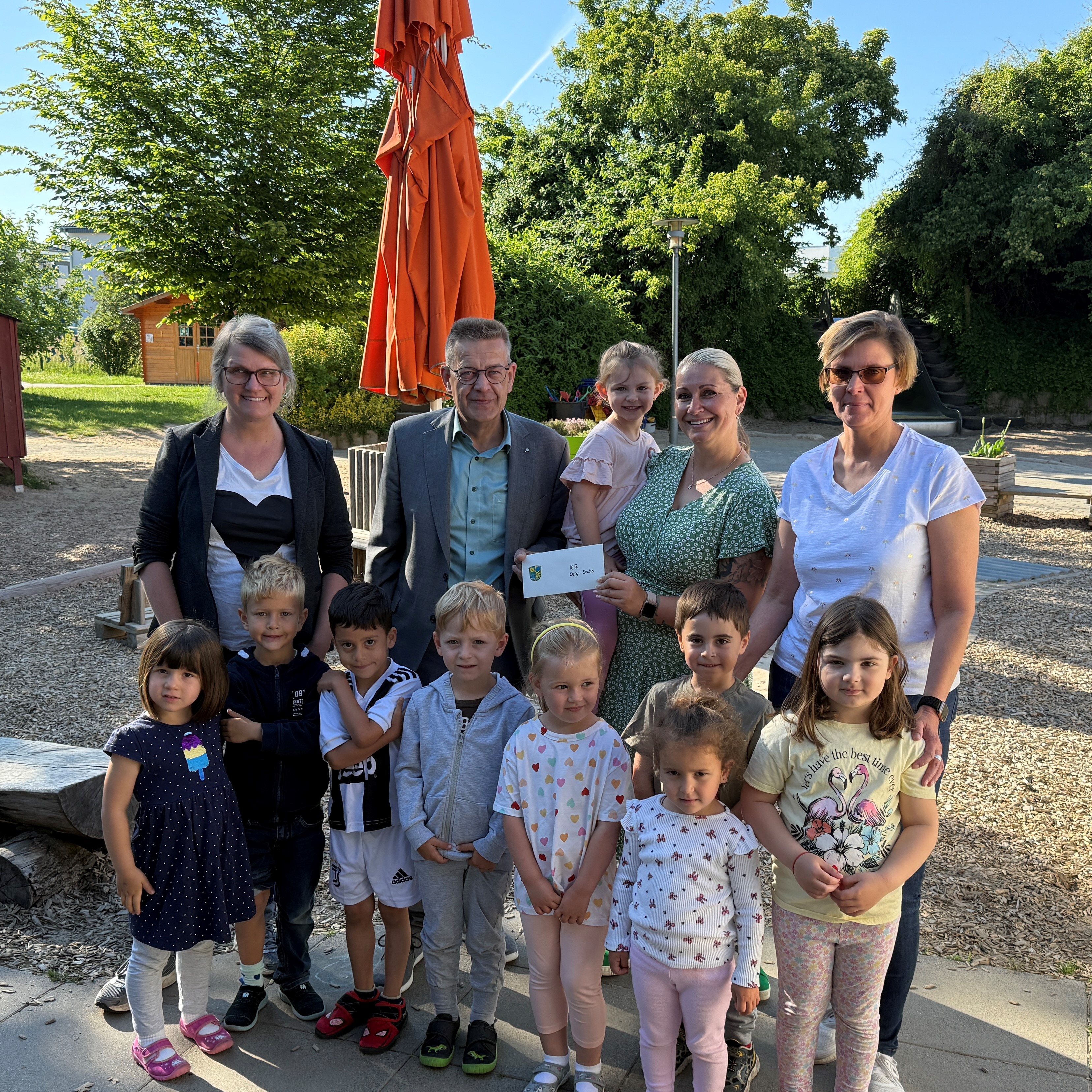 Kinder, KiTa-Leitungen, Bürgermeister Stefan Erb und Fachdienstleitung Sandra Wunder bei der Übergabe eines Geschenkgutscheins