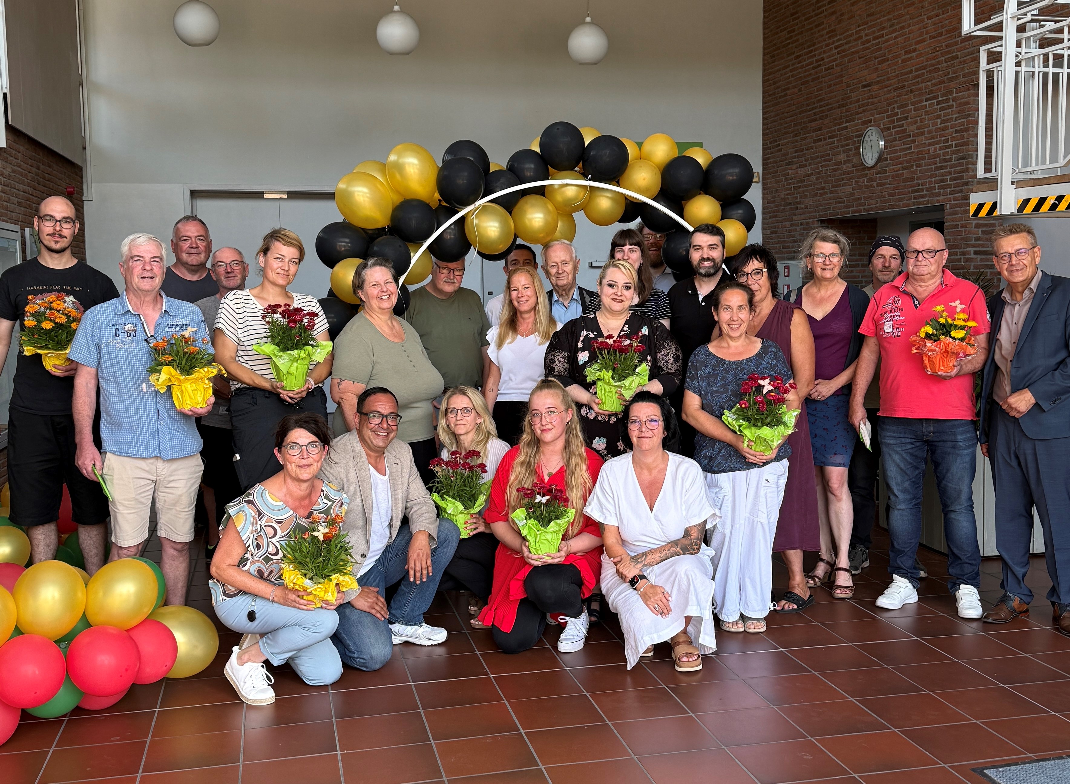 Gruppenbild mit Stefan Erb und den neuen Beschäftigten mit Blumensträußen