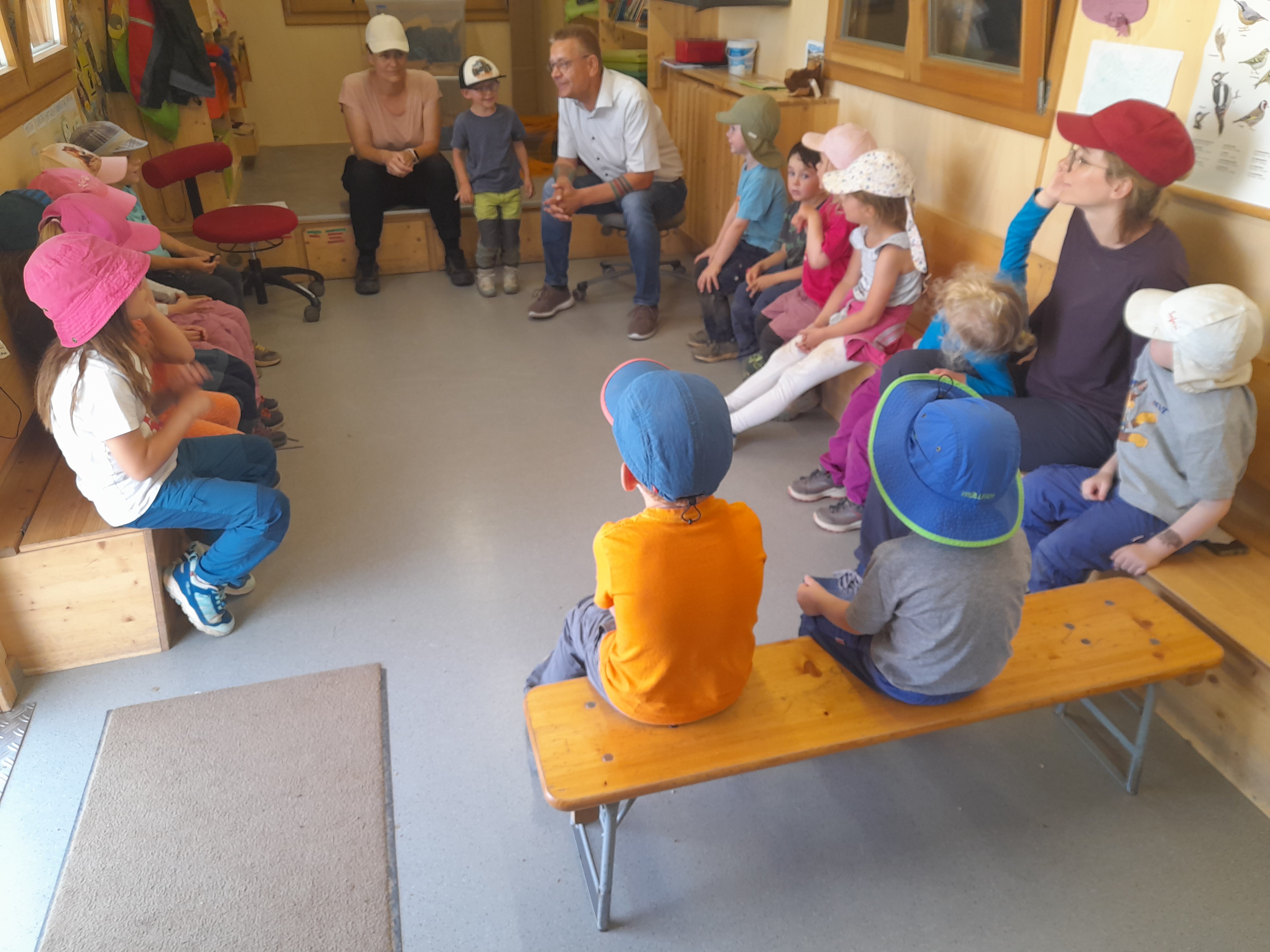 Bürgermeister sitzt mit Kindern in einem Bauwagen im Gespräch