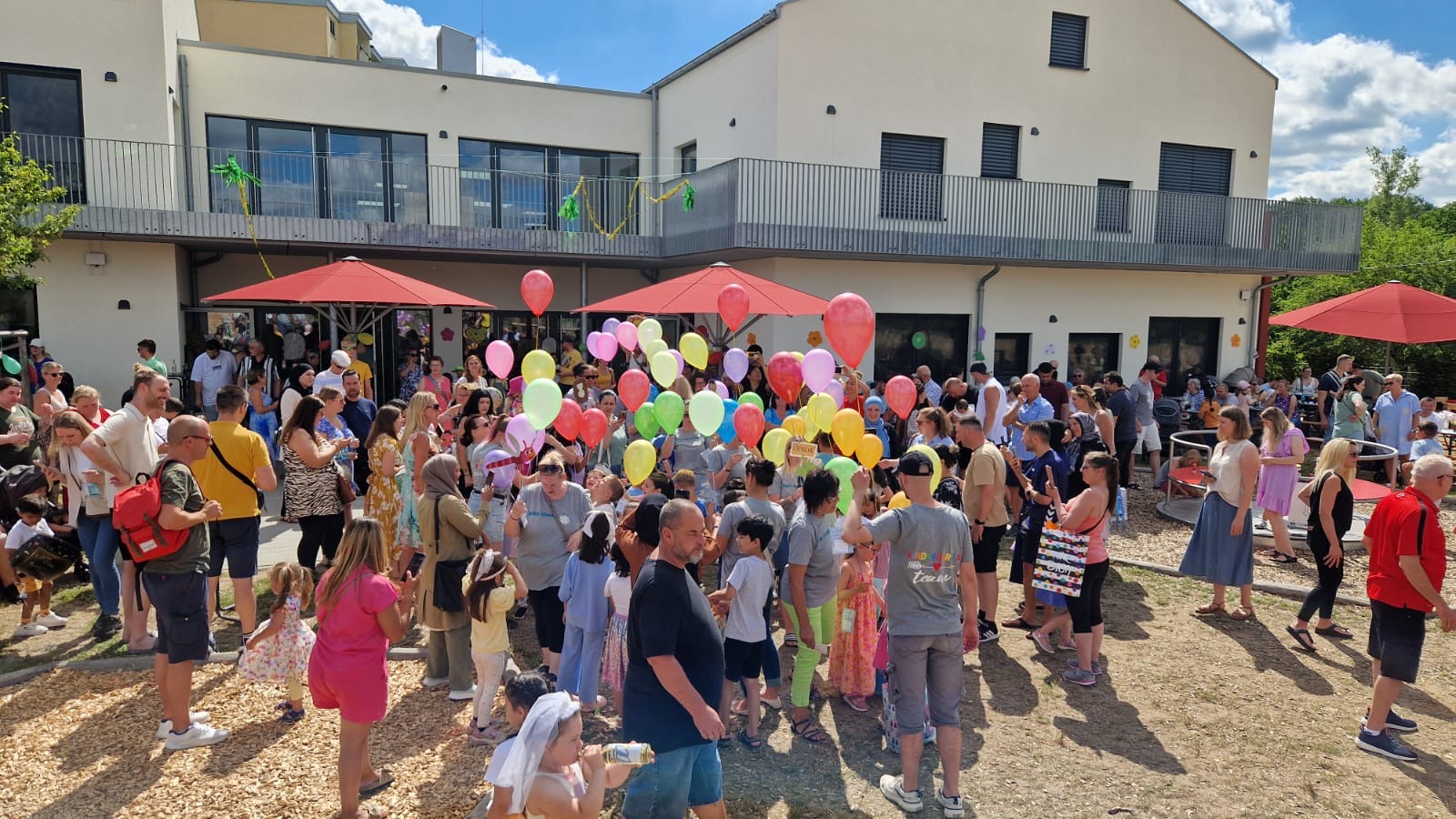 Außengelände der KiTa mit vielen Menschen und Luftballons