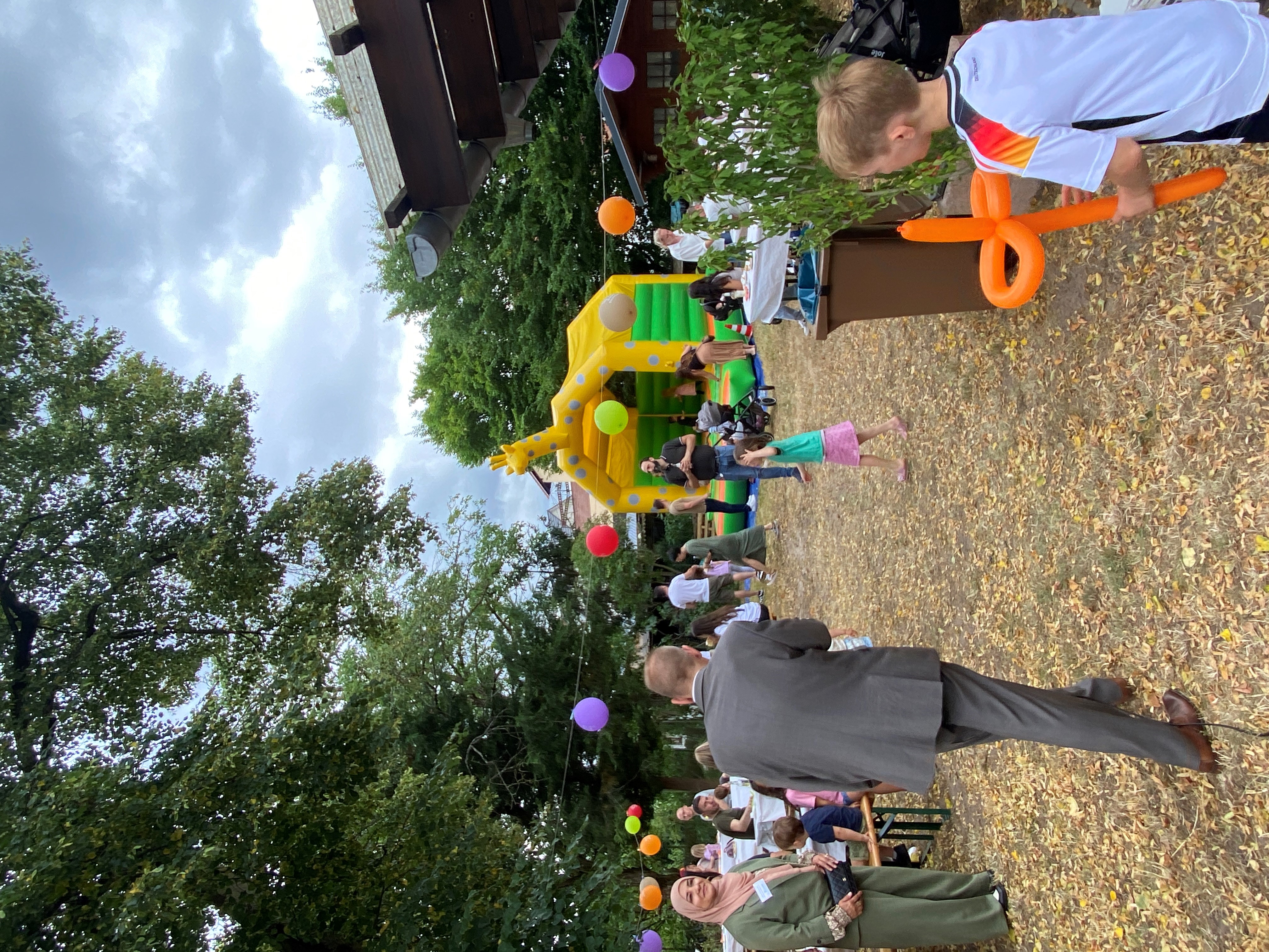 Gelände des Sommerfestes mit Hüpfburg, Tischen und Luftballons