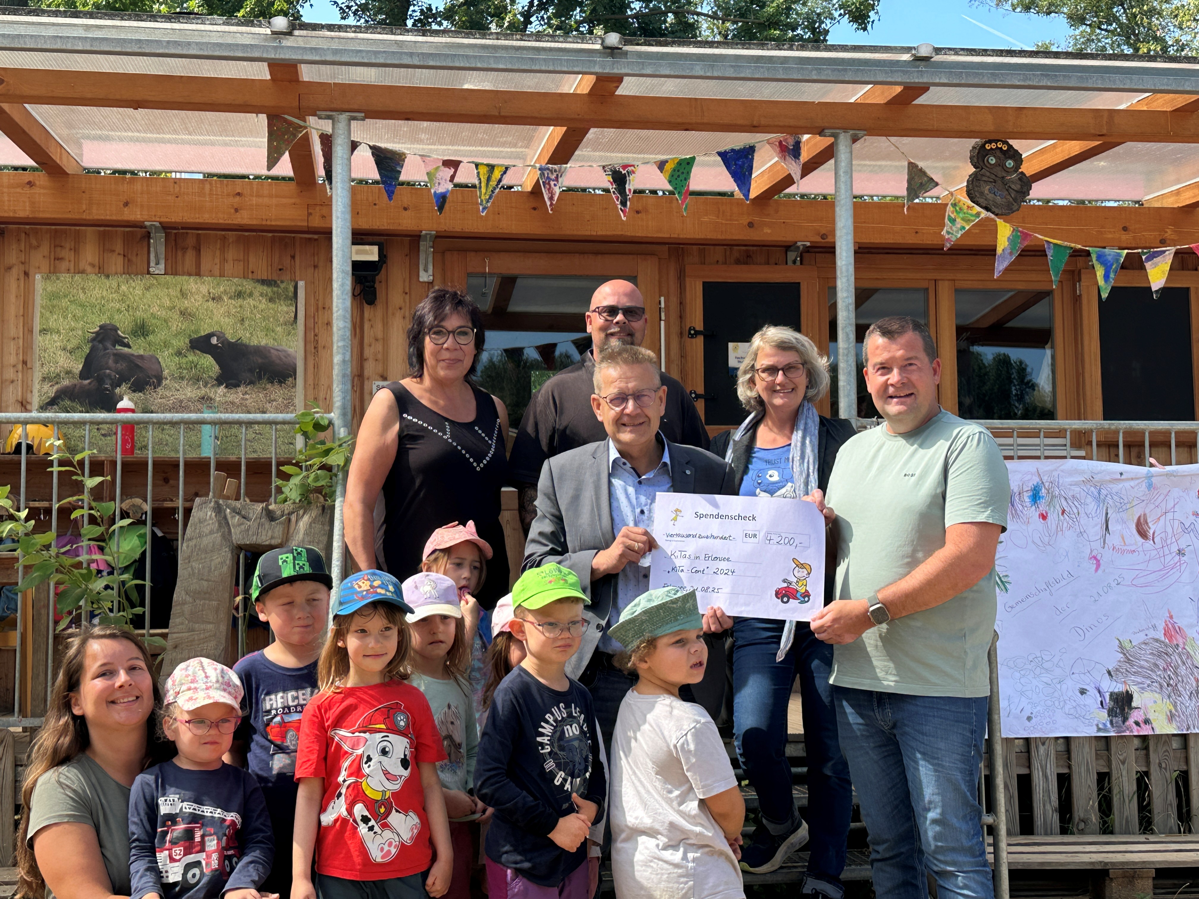 Michael Reising von REWE-Reising überreicht Bürgermeister Stefan Erb den symbolischen Spendenscheck in Höhe von 4200,- € in der Natur-KiTa im Limespark