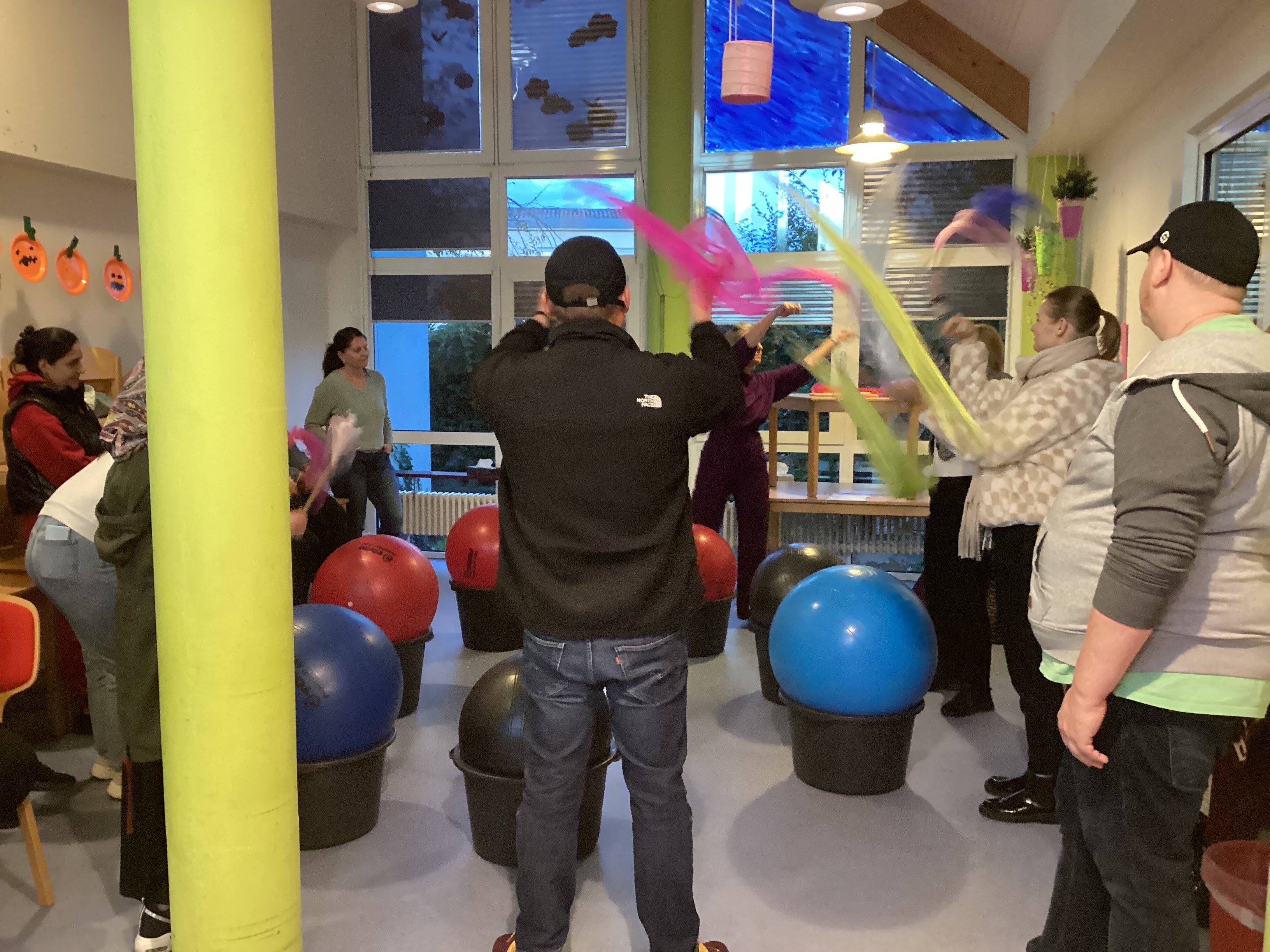 Eltern in Bewegung mit Bällen, Tücjern und Trommelstöcken