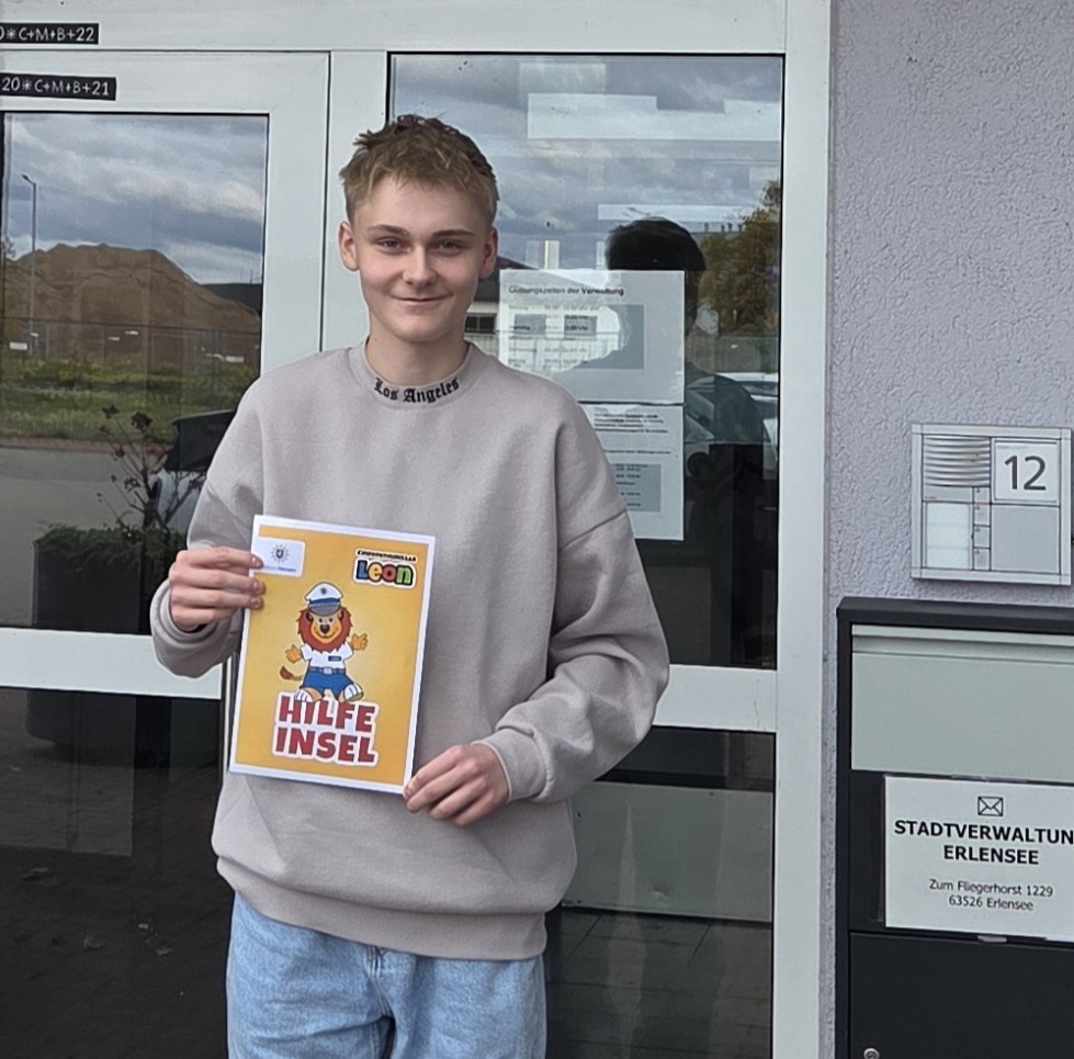 Praktikant Jannik Stadtmüller mit dem Plakat der Leon-Hilfeinsel