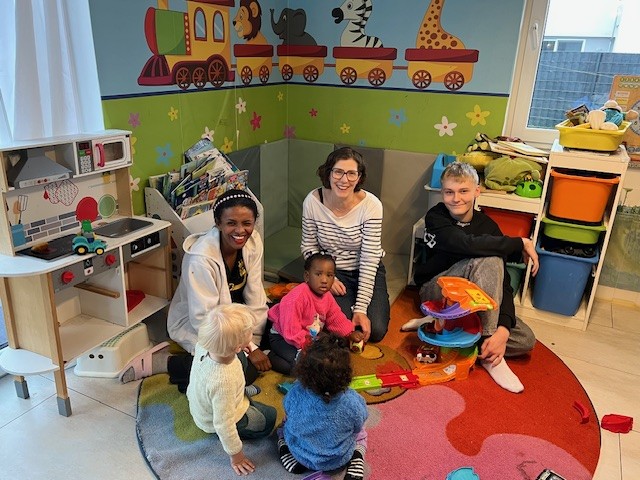 Heaven Zewdu-Tekeste, Kathrin Smola-Peter und Praktikant Jannik Stadtmüller mit den Betreuungskindern in der Spielecke