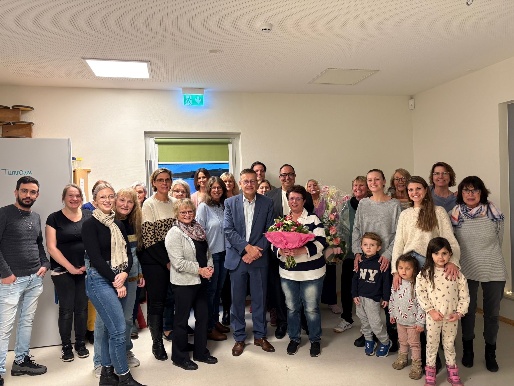 Gabriele Hilke mit Blumenstrauß, Bürgermeister Stefan Erb und viele Gratulanten von der KiTa Nelly Sachs