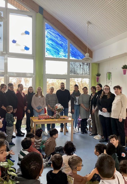 Ellen Marek mit Blumenstrauß, vielen Kindern und pädagogischem Personal