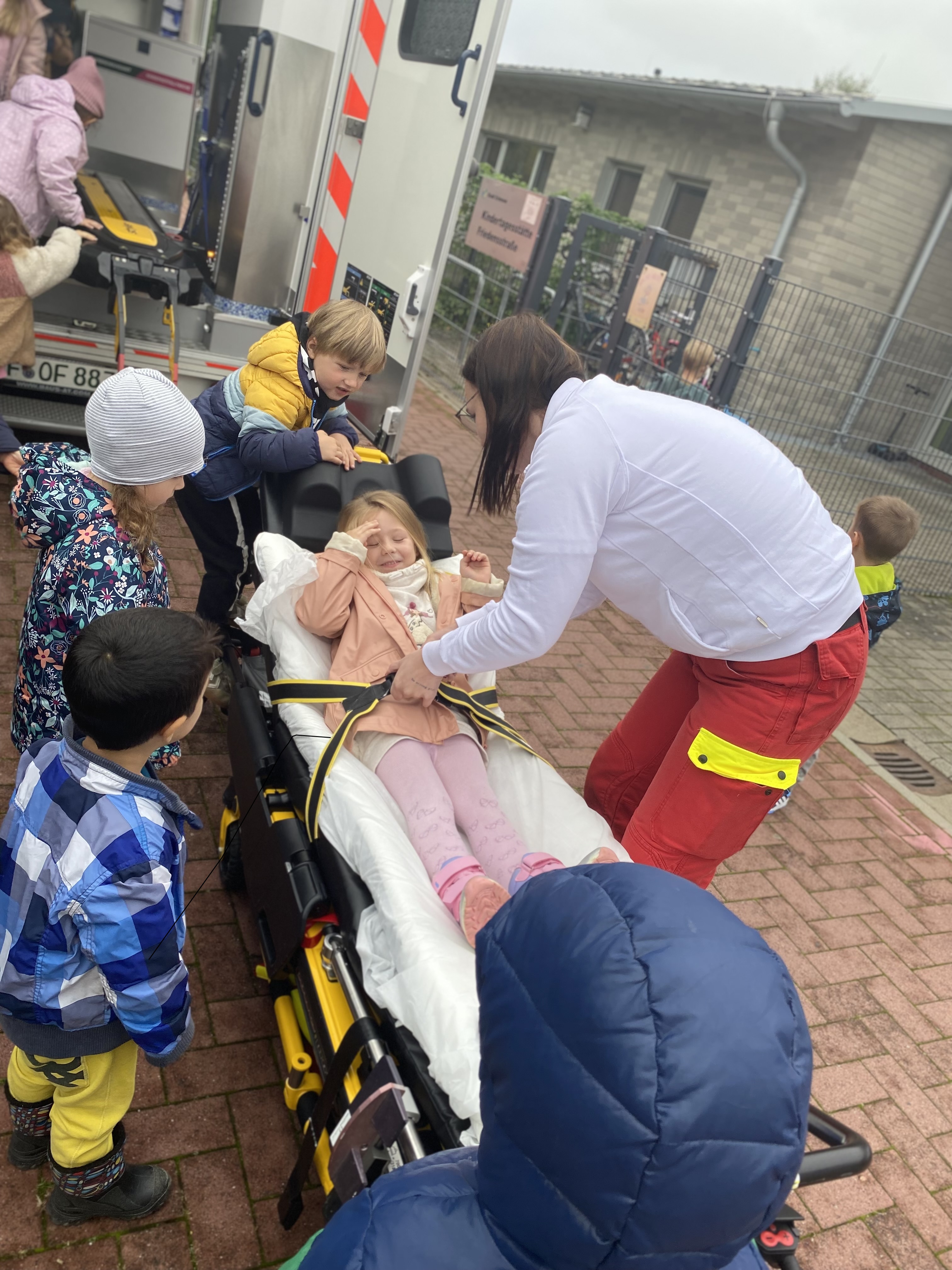 Ein Kind wird von einer Sanitäterin im Spiel auf einer Trage festgeschnallt