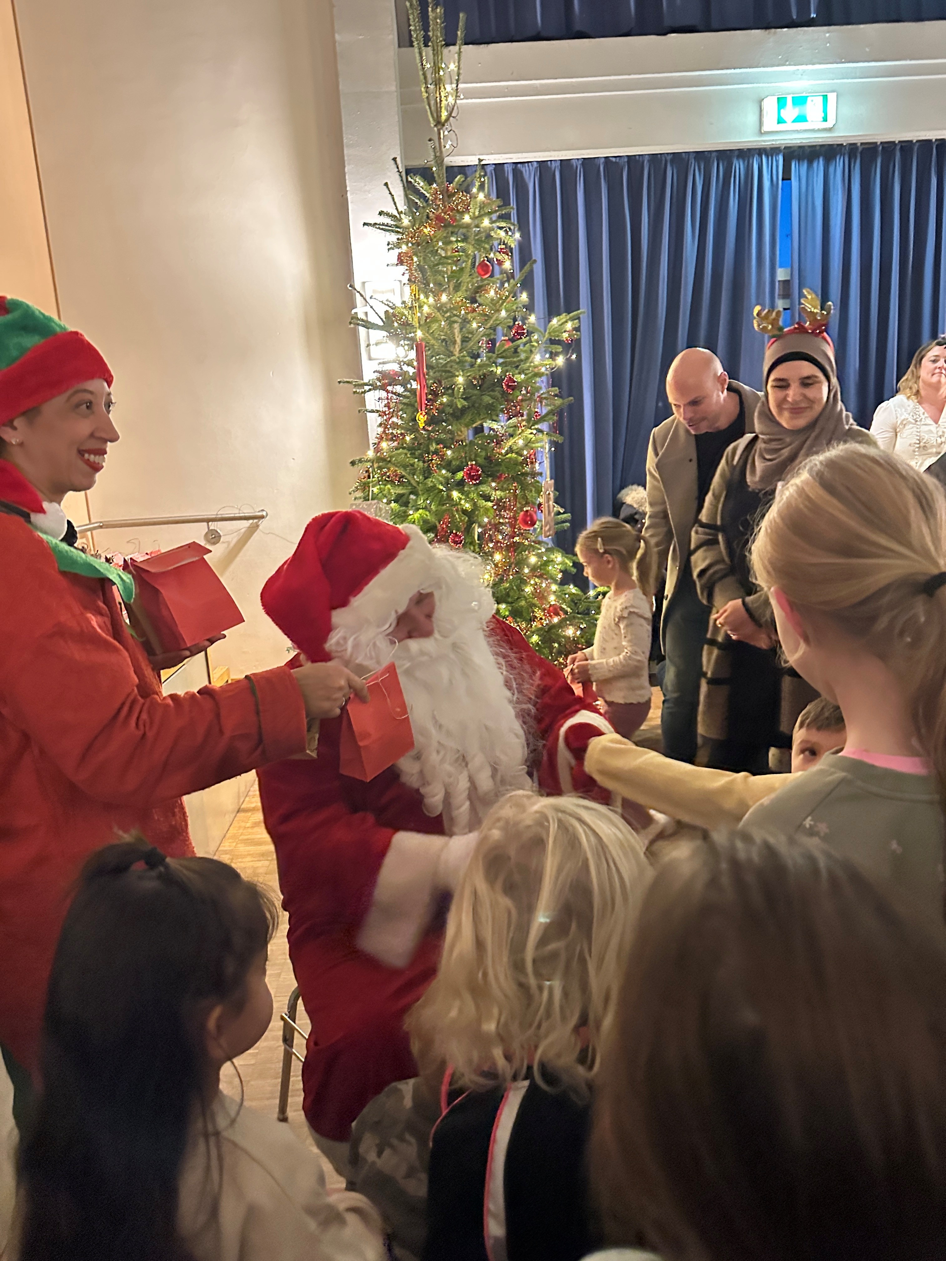 Der Nikolaus mit seinem Elf umringt von vielen Kindern