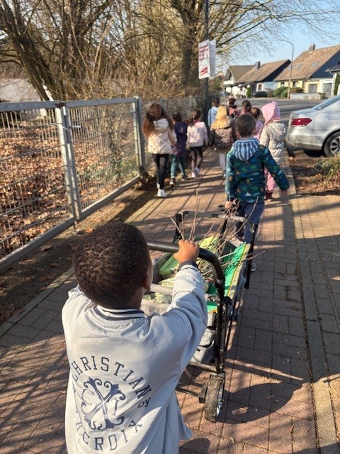 KiTa-Kinder auf dem Weg zum Seniorenheim mit Bollerwagen voll Bastelmaterial