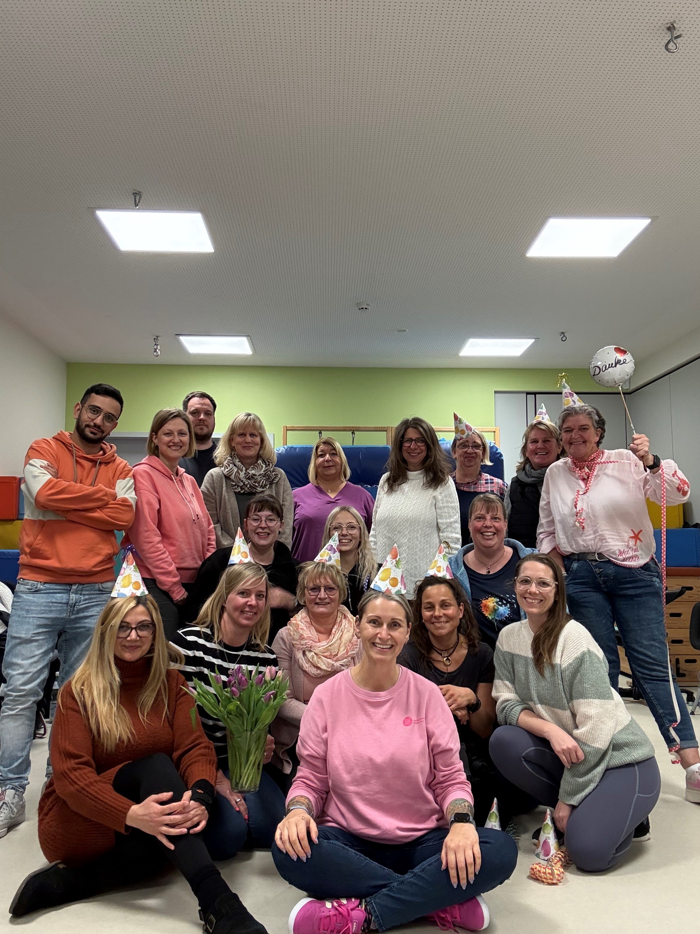 Das Team KiTa Nelly Sachs feiert mit Luftballons und Hütchen