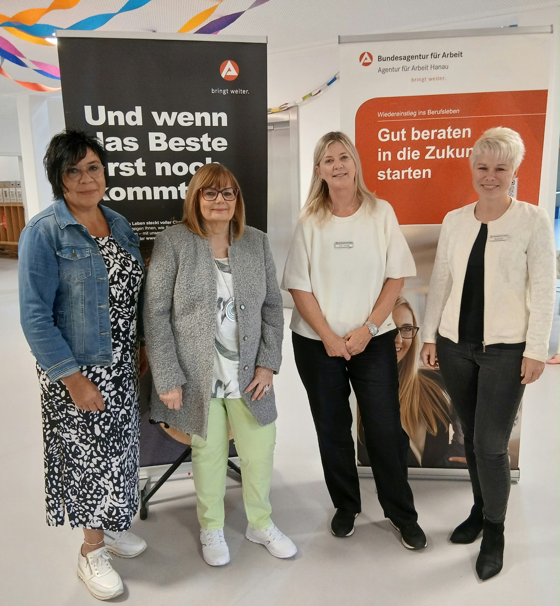 Frau Ute Leonhardt die Leitung der Kita Leipziger steht zusammen mit Frau Elvira Horst aus dem Magistrat sowie den Fachkräften der Agentur für Arbeit, Frau Ruth Hohage und Frau Lynn Beeskow vor zwei Informationstafeln.