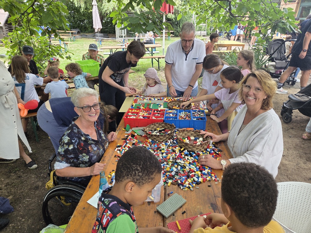 Die Lego Oma Rita Ebel beim Bauen einer Lego Rampe mit einigen Kindern, deren Eltern und weiteren Familienangehörigen oder Bekannten