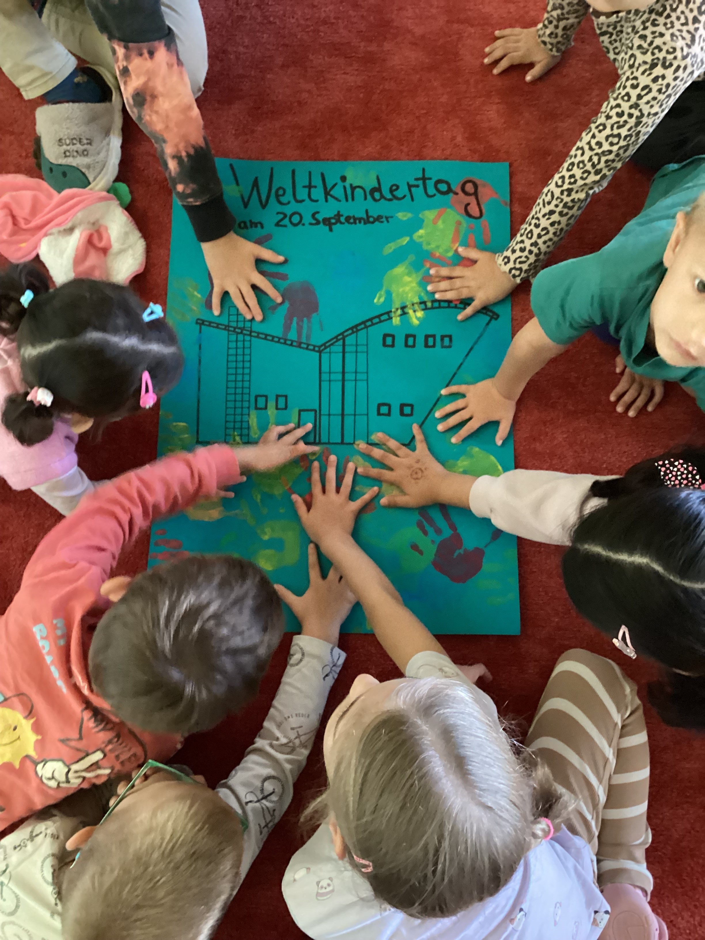 Die Kinder setzen ihre Handabdrücke mit Fingerfarben auf ein Plakat anlässlich des Weltkindertages am 20. September